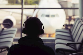 Man met koptelefoon met ruisonderdrukking op de luchthaven